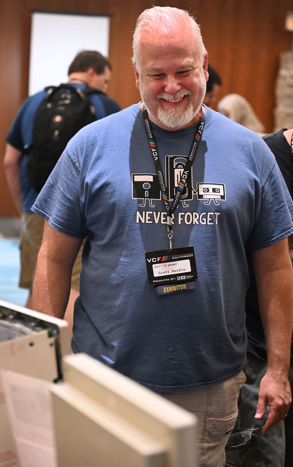 Smiling man in blue t-shirt looking at a vintage computer.