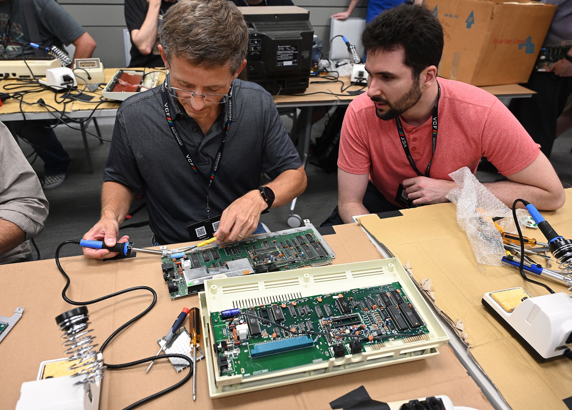 Two men repairing a vintage computer chip board.