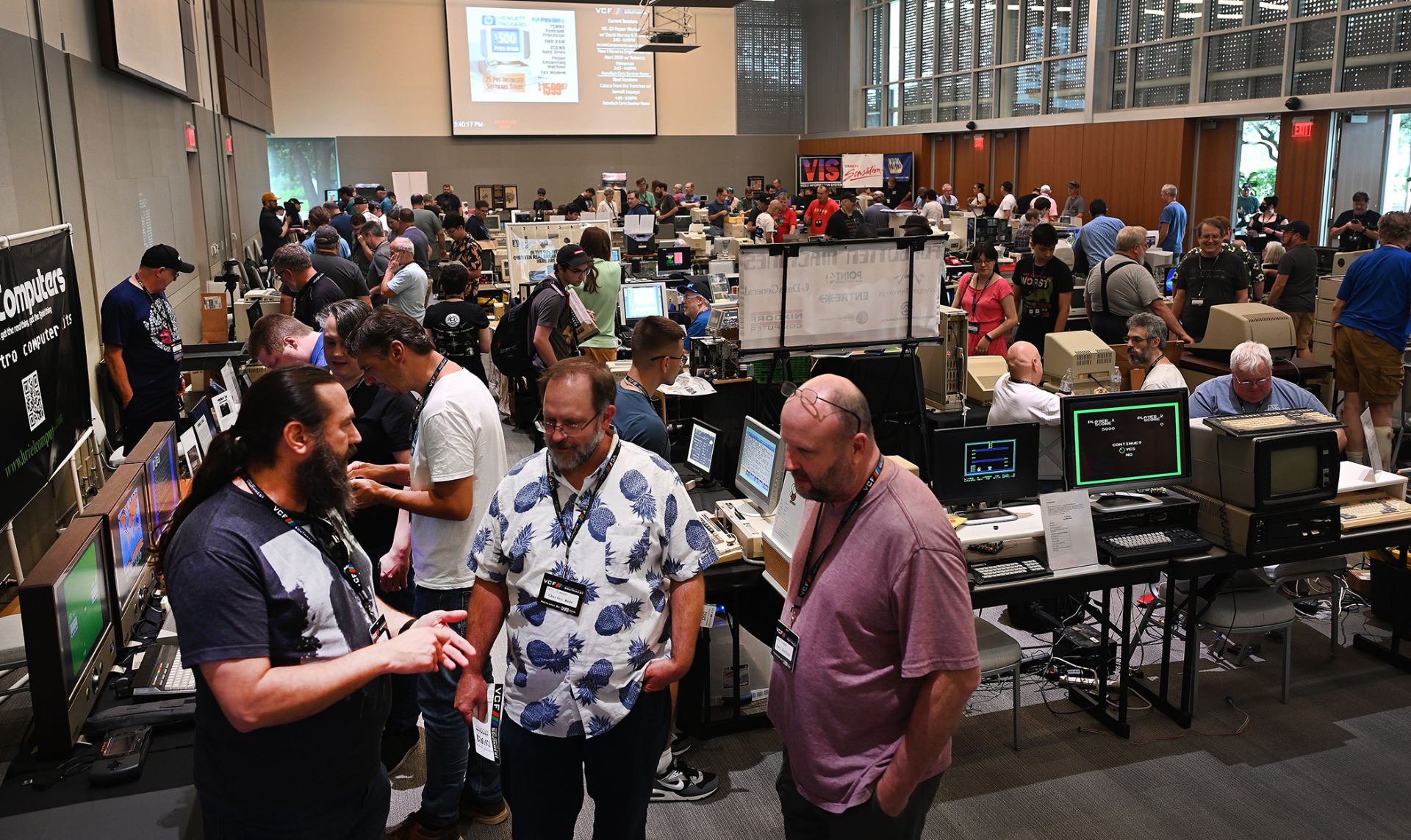 Large group of people gathered at a vintage computer exhibit.